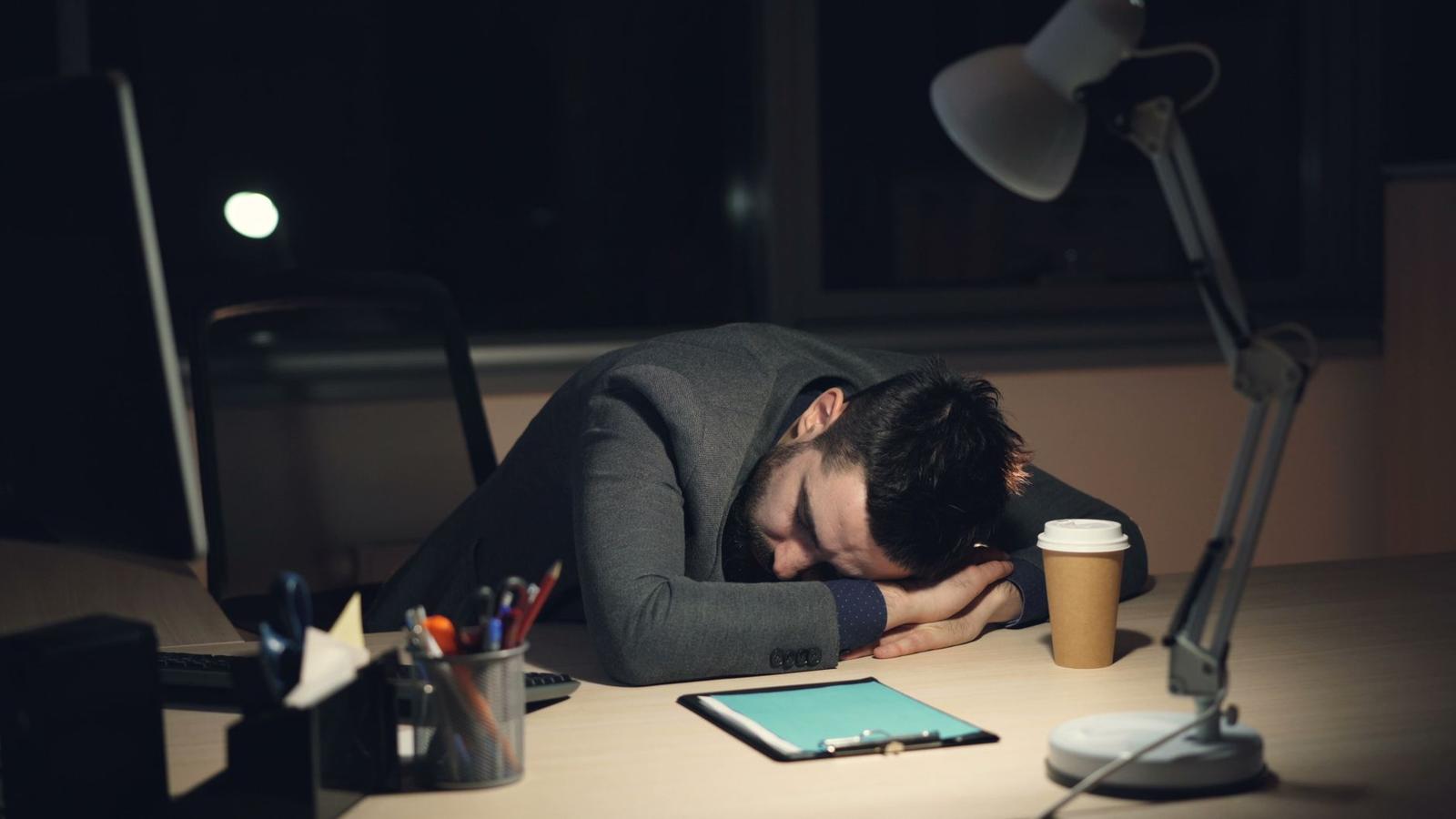 Exhausted Worker Sleeping at Desk Late Night